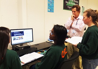 Access2online Coordinator Peter Shikli and three inmates discussing a task